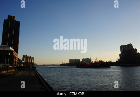 Lever du soleil Ciel bleu, vue en direction de Robert Kennedy, pont chaland de charge se déplace vers le sud de l'Île Roosevelt silhouette, East River, New York Banque D'Images