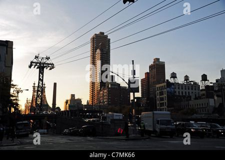 Ciel bleu sur l'aube des réservoirs d'eau, maisons, téléphérique, pylône Queensboro Bridge du trafic à l'intersection 2e Avenue, New York City Banque D'Images