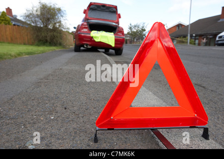 Triangle de présignalisation disposés sur le côté de la route dans un quartier résidentiel derrière une voiture en panne Banque D'Images