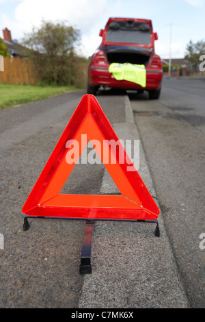 Triangle de présignalisation disposés sur le côté de la route dans un quartier résidentiel derrière une voiture en panne Banque D'Images