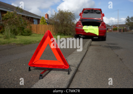 Triangle de présignalisation disposés sur le côté de la route dans un quartier résidentiel derrière une voiture en panne Banque D'Images