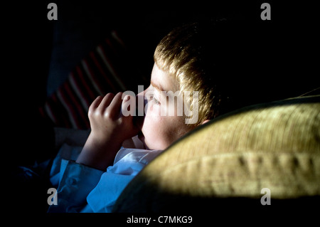 Jeune garçon fatigué suçant son pouce sur le canapé tout en regardant la télévision.lit-temps, garçon, enfant, rêve, sieste, nuit, sle Banque D'Images