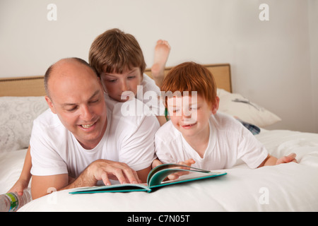 Un père et ses deux fils lire ensemble Banque D'Images