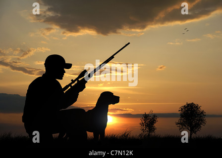 Chasseur et son chien silhouettes sur fond coucher de soleil Banque D'Images