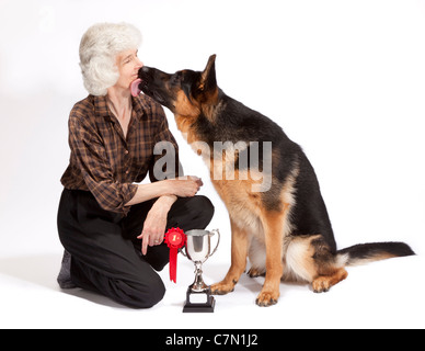 Jeune mâle berger allemand de lécher sa propriétaire après avoir remporté un trophée pour gagner la première place Banque D'Images