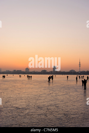 Congelés fermement, l'Aussenalster Lac Alster, après le coucher du soleil, les gens, l'amusement, glace, neige, hiver, Hambourg, Allemagne Banque D'Images