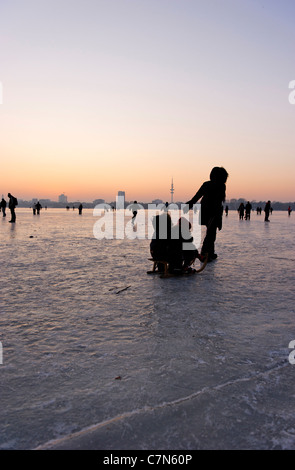 Congelés fermement, l'Aussenalster Lac Alster, après le coucher du soleil, les gens, l'amusement, glace, neige, hiver, Hambourg, Allemagne Banque D'Images