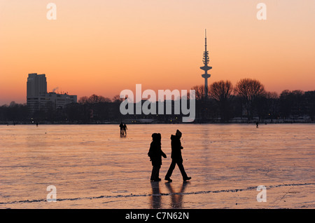 Congelés fermement, l'Aussenalster Lac Alster, après le coucher du soleil, les gens, l'amusement, glace, neige, hiver, Hambourg, Allemagne Banque D'Images