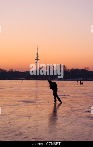 Congelés fermement, l'Aussenalster Lac Alster, après le coucher du soleil, les gens, l'amusement, glace, neige, hiver, Hambourg, Allemagne Banque D'Images