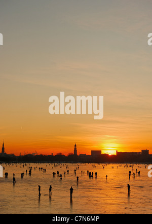 Congelés fermement, l'Aussenalster Lac Alster, après le coucher du soleil, les gens, l'amusement, glace, neige, hiver, Hambourg, Allemagne Banque D'Images