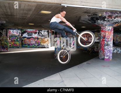 Grafitti-terrain sur la rive sud, Londres- cycliste acrobatique Banque D'Images