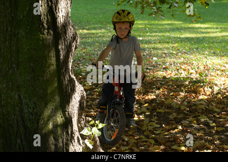 Enfant garçon blond 5 ans équitation vélo avec casque de sécurité dans la région de autumn park Banque D'Images