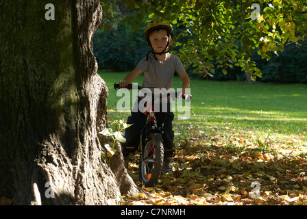 Enfant garçon blond 5 ans équitation vélo avec casque de sécurité dans la région de autumn park Banque D'Images