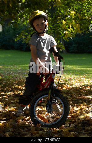 Enfant garçon blond 5 ans équitation vélo avec casque de sécurité dans la région de autumn park Banque D'Images