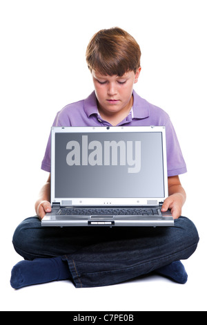 Un garçon de 11 ans avec un ordinateur portable, isolé sur blanc avec chemin de détourage pour l'écran vide. Banque D'Images