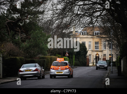 Les instructeurs de conduite BSM arrondit un voiture Mercedes stationnaire dans une rue de banlieue typiquement britannique en Angleterre Banque D'Images