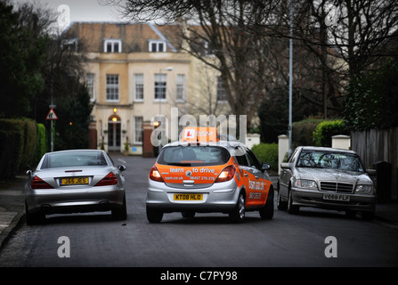 Les instructeurs de conduite BSM inverse autour d'une voiture Mercedes stationnaire dans une rue de banlieue typiquement britannique en Angleterre Banque D'Images