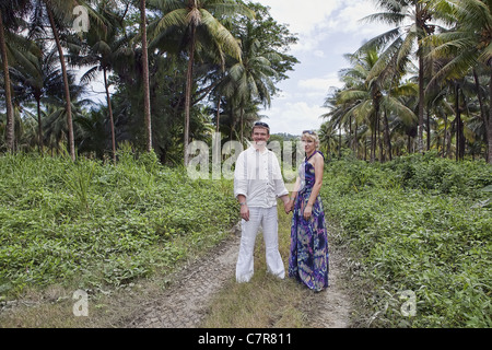 Couple Debout, côte à côte dans une forêt de cocotiers de la Jamaïque Banque D'Images