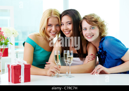 Portrait de trois copines assis dans un café, looking at camera and smiling Banque D'Images