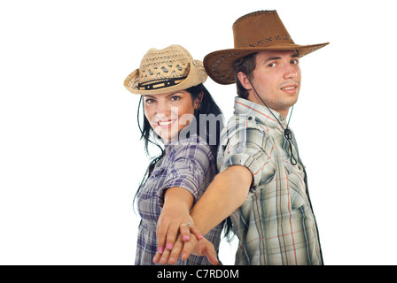 Couple heureux dans des chapeaux de cow-boy debout dos à dos et se tenant la main en face de l'appareil isolé sur fond blanc Banque D'Images