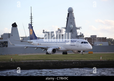 Boeing 318 Lufthanas au London City Airport avec un destroyer de Type 45 de la Royal Navy dans l'arrière-plan Banque D'Images