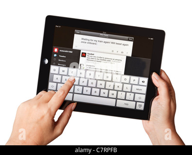 Mains féminines utilisant un vieil iPad écrivant un tweet sur une application mobile Twitter Banque D'Images