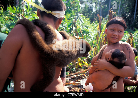 Les populations autochtones Korubo Amazon Brésil singe homme porte sur ses épaules comme un animal de compagnie tout en femme porte son bébé dans les bras Banque D'Images