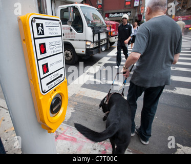 Les déficients visuels l'homme avec son chien d'traverse une intersection à New York Banque D'Images