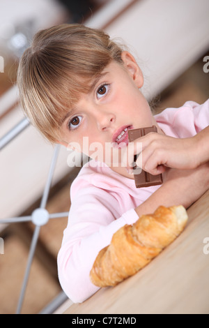 Jeune fille avec un croissant et barre de chocolat Banque D'Images