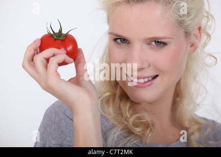Un blond woman holding une tomate dans la main Banque D'Images