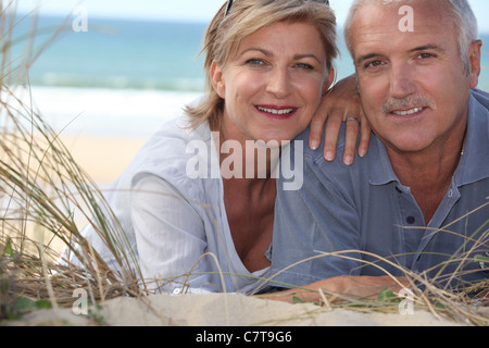 Couple d'âge moyen se situant dans les dunes de sable Banque D'Images