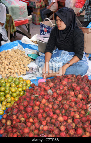 Vente Dame indonésien et ramboutan oranges sur son échoppe de marché Banque D'Images
