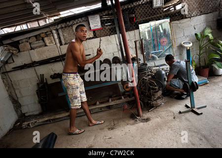 Un jeune homme Cubain ne l'exercice de remise en forme avec des barres à une salle de sport dans le culturisme, Alamar La Havane, Cuba. Banque D'Images