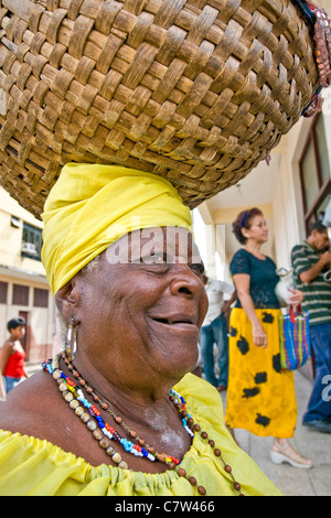 Cuba, Santiago, senior woman carrying basket on head Banque D'Images