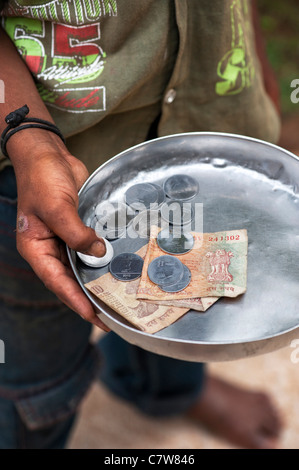 Les jeunes Indiens de caste inférieure pauvre garçon des rues mendier avec plaque d'argent. L'Andhra Pradesh, Inde. selective focus Banque D'Images