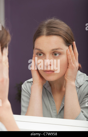 Le vieillissement de la peau contrôle de la femme dans le miroir Banque D'Images