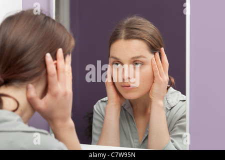 Le vieillissement de la peau contrôle de la femme dans le miroir Banque D'Images