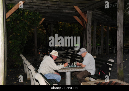 Deux hommes âgés jouant aux échecs sur une table en béton sous une pergola rustique, Echecs et vérificateurs House, Central Park, New York City Banque D'Images