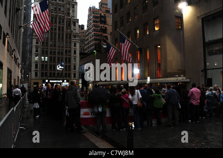 Tôt le matin, foule regardant 'Today Show' ci-dessous, des drapeaux américains, les studios NBC News pavés humides Rockefeller Plaza, New York City Banque D'Images