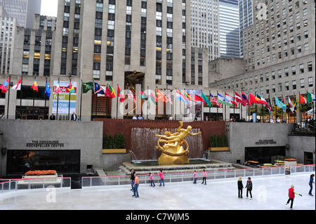Voir -glace, patineurs sur glace blanc doré sculpture avant Prométhée GE Building drapeaux, Patinoire Rockefeller, New York City Banque D'Images