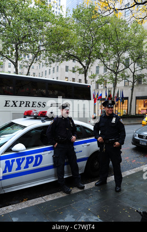 Deux policiers du NYPD qui pose pour une photographie sur le côté d'une voiture de police, 49th Street, près de NBC News, Rockefeller Center, New York Banque D'Images