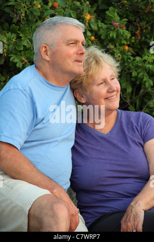 Couple marié Senior affichage coucher du soleil smiling sitting on rocks Banque D'Images