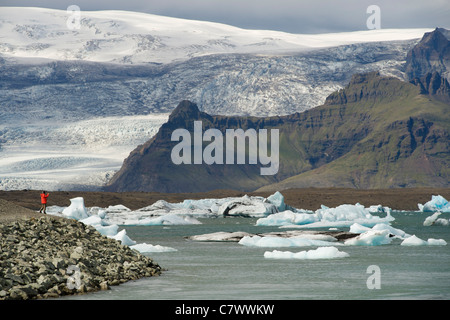 Tourist photographing icebergs flottant dans le lac Jokullsarlon au pied du glacier de Vatnajokull dans le sud-est de l'Islande. Banque D'Images