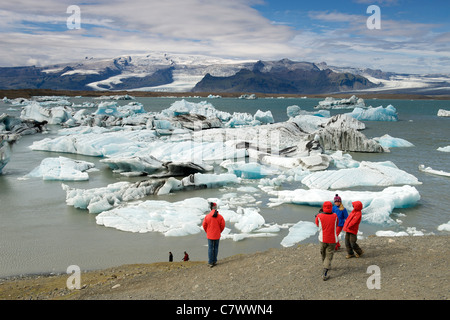 Les touristes regardant les icebergs flottant dans le lac Jokullsarlon au pied de l'énorme glacier de Vatnajokull dans le sud-est de l'Islande. Banque D'Images