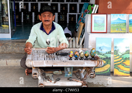 Artiste Wayan Rana, la peinture des œufs, à l'extérieur de son magasin dans Village Sebali, près de Ubud. Bali, Indonésie. Parution du modèle Banque D'Images