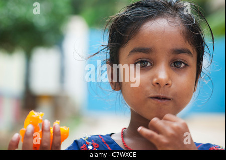 Jeunes pauvres caste inférieure Indian street girl holding et manger un doux traditionnel indien. Jaangiri / Jangiri / Imarti. Focus sélectif. Banque D'Images