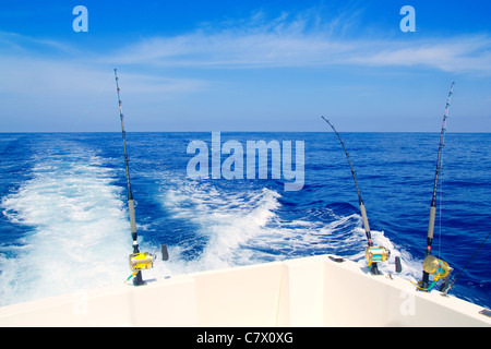 Bateau de pêche à la traîne dans la mer d'un bleu profond avec des cannes et moulinets Banque D'Images