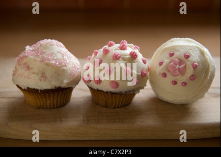 Cupcakes rose et blanc givré diverses conceptions sur la plaque à gâteau et rétroéclairé comptoir Banque D'Images