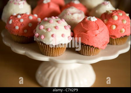 Cupcakes rose et blanc givré diverses conceptions sur la plaque à gâteau et rétroéclairé comptoir Banque D'Images