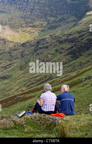 Les randonneurs s'asseoir pour déjeuner avec vue sur l'Honister Pass in Borrowdale partie du Lake District, Cumbria, Angleterre Banque D'Images
